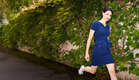 lady in blue dress walking past a green wall